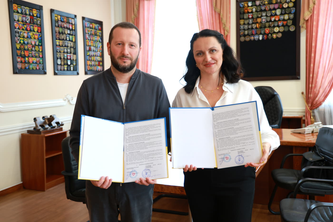 Голова Хмельницької ОВА Сергій Тюрін і засновниця БФ «Твоя опора» Валерія Татарчук тримають підписані примірники меморандуму